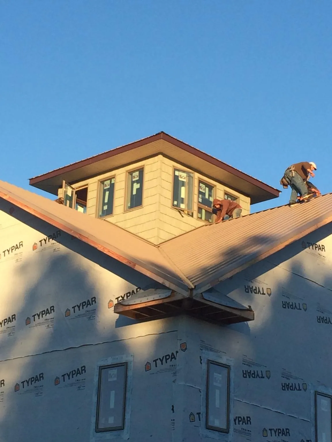 Roofers working around a rooftop cupola on a new metal roof at sunset — Roof Waterproofing in Salida by Roofing Brothers